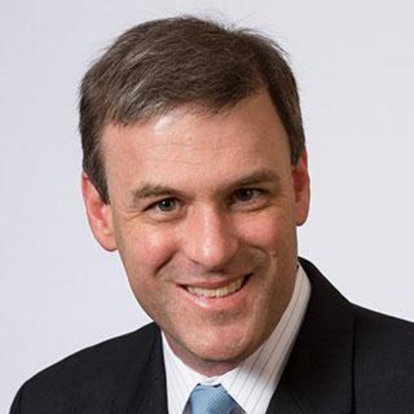 Blog featured image. Headshot of a 40something White man in a dark suit, with short brown hair and a boyish grin.