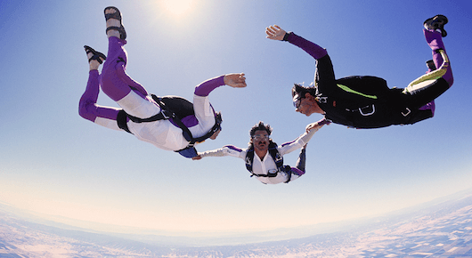 Illustration of five skydivers in formation holding hands in the sky with clouds below