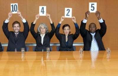 Four judges holding rating score cards at a table