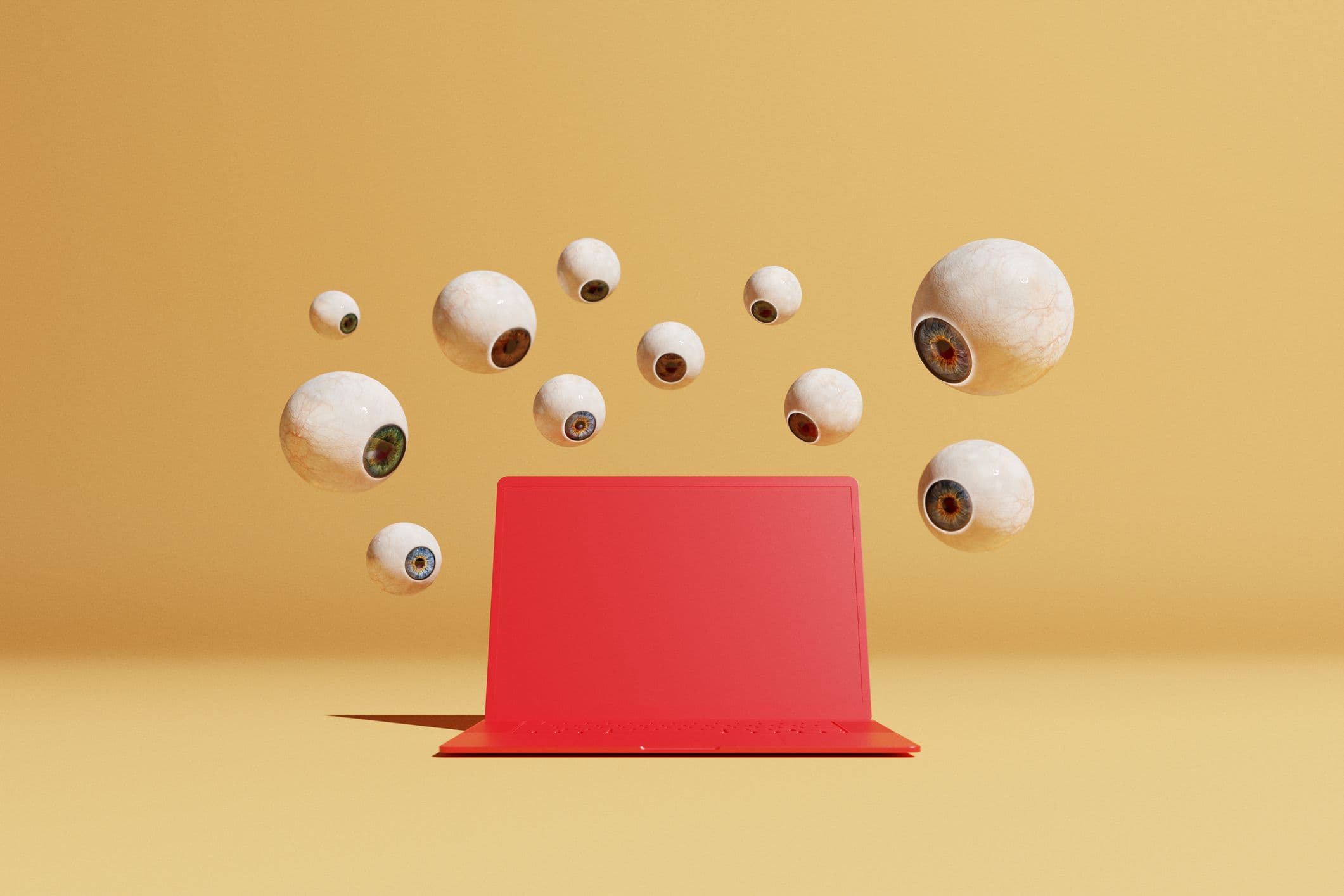 A flock of floating eyeballs stare down at a red laptop.