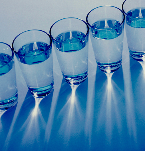 A photo of glasses of water in a diagonal row and seen from above.