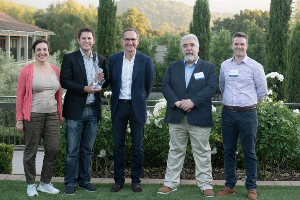 Photograph of five people at an awards event with scenic outdoor backdrop