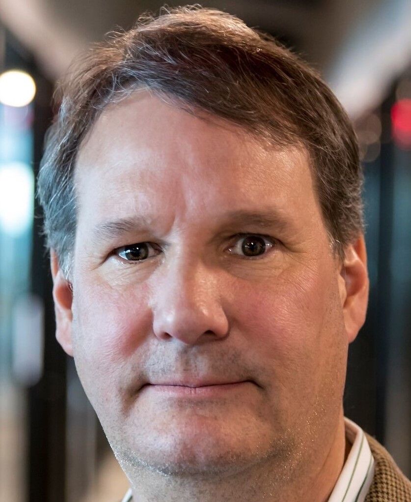 A photo of a clean-shaven middle-aged White man with brown hair and brown eyes.