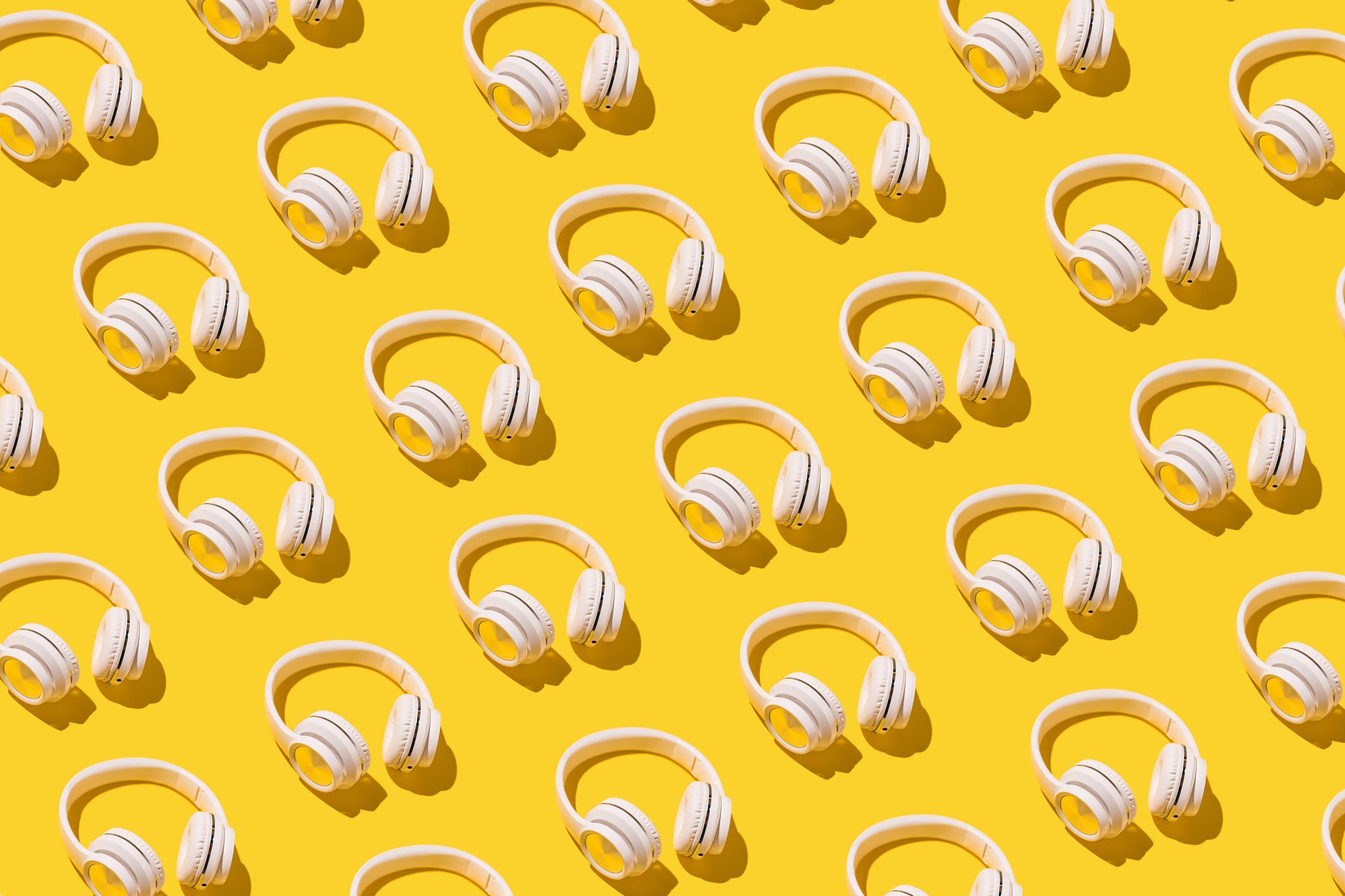 An image of headphones in diagonal rows against a bright yellow field.