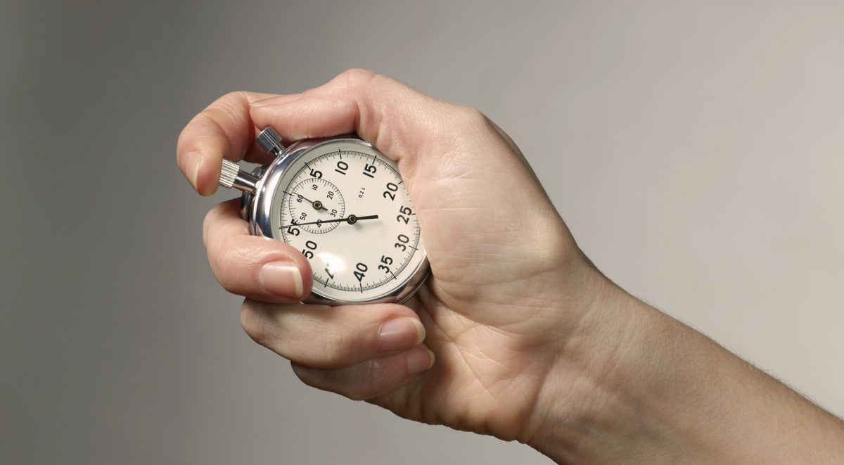 Hand holding an analog stopwatch