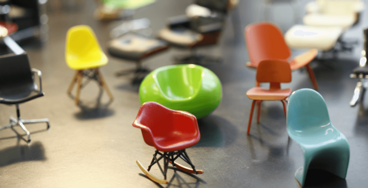 A collection of miniature designer chairs in swooping shapes and bright colors.