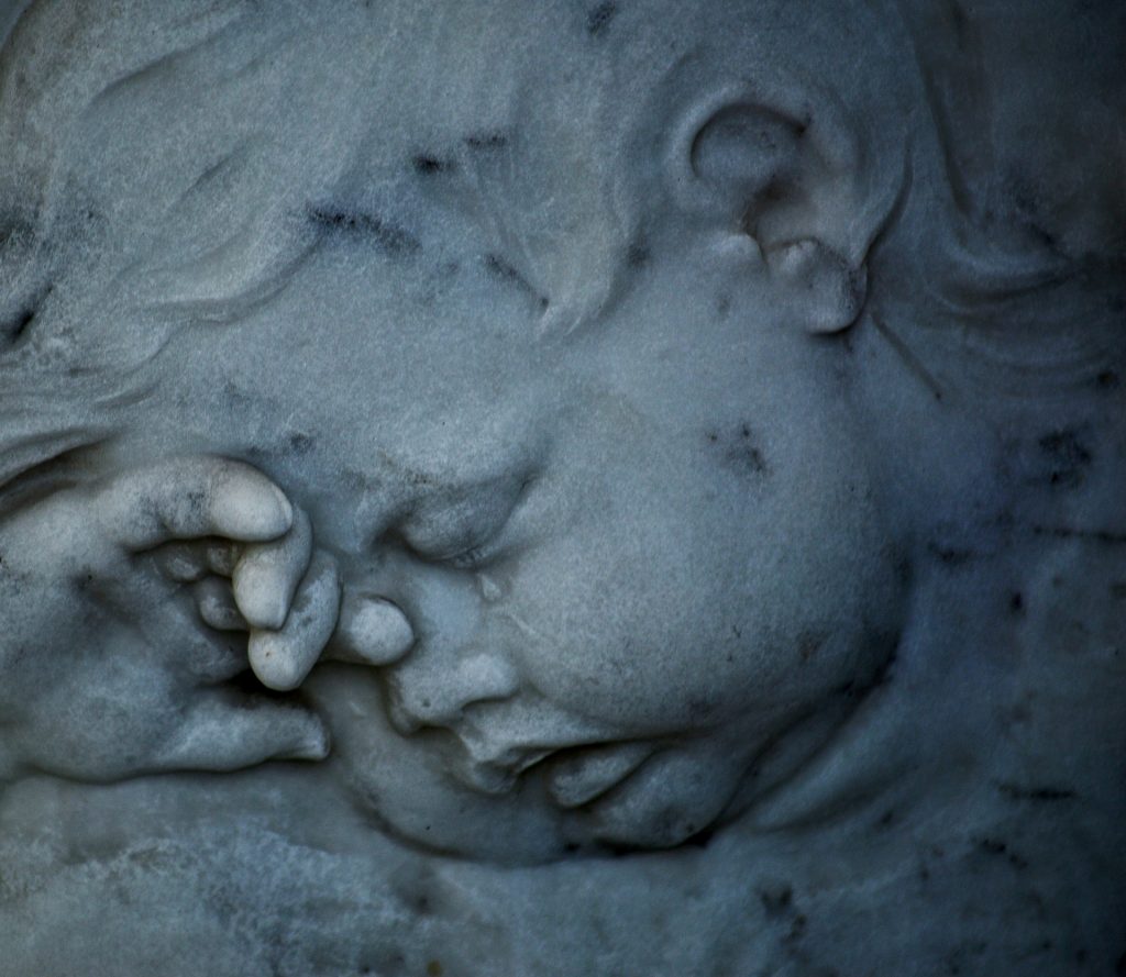 Stone sculpture of a sleeping cherub angel figure