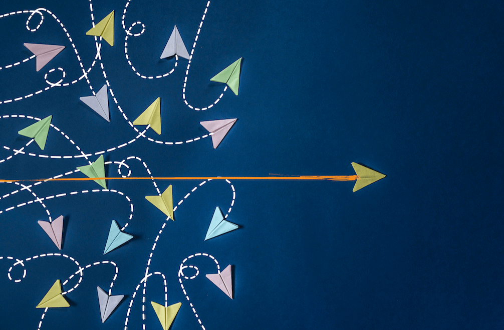 On a dark blue field, multicolor illustrated arrows swirl and veer while one arrow shoots straight across from left to right.