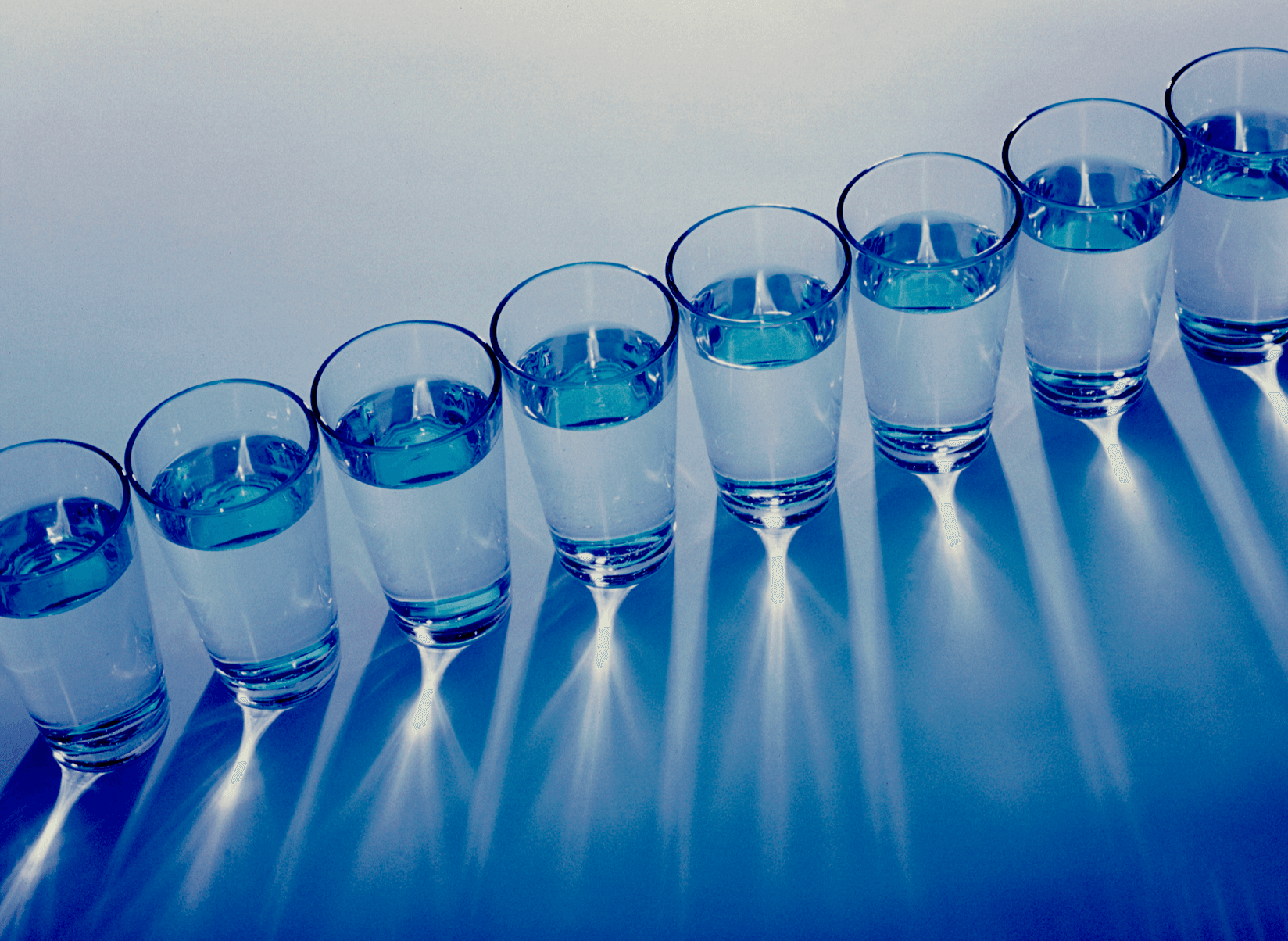 A photo of glasses of water in a diagonal row and seen from above.