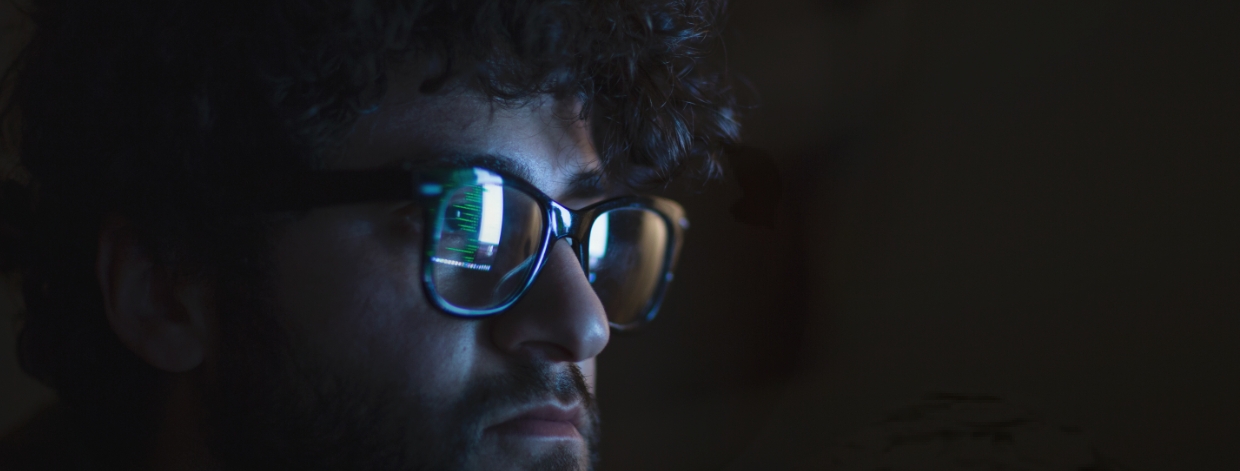 stock image: face in dark room lit by glow of a computer monitor