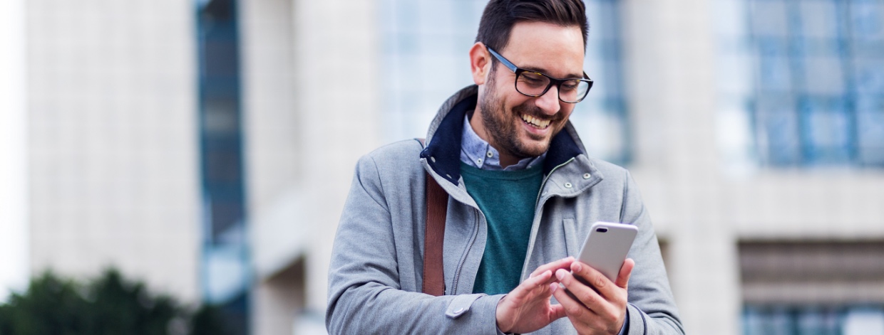 stock image: smiling man in jacket looking at smartphone