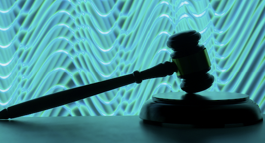 A brown silhouetted gavel leans on a block against a backdrop of swirling blue lines.