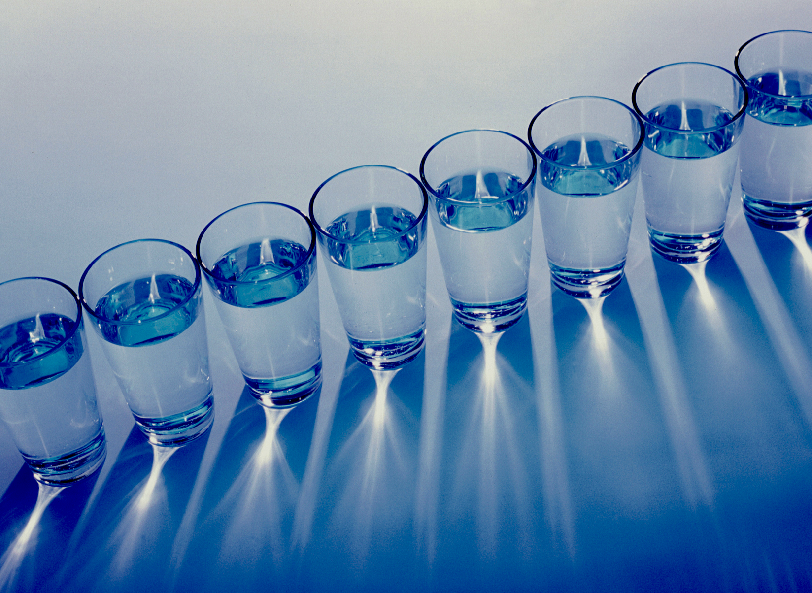 A photo of glasses of water in a diagonal row and seen from above.