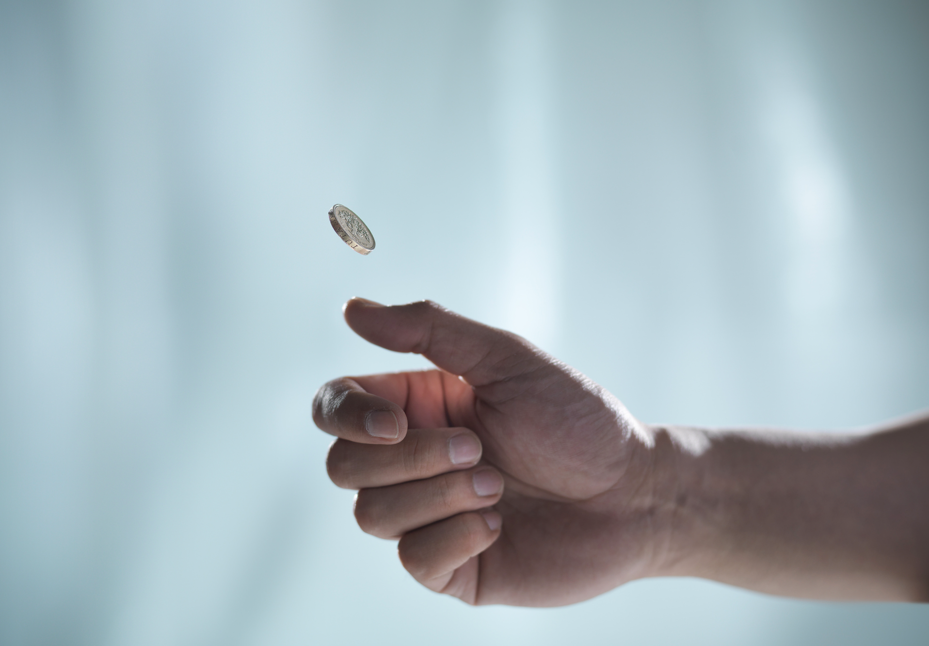 Photo of a hand flipping a coin that hangs in mid air.