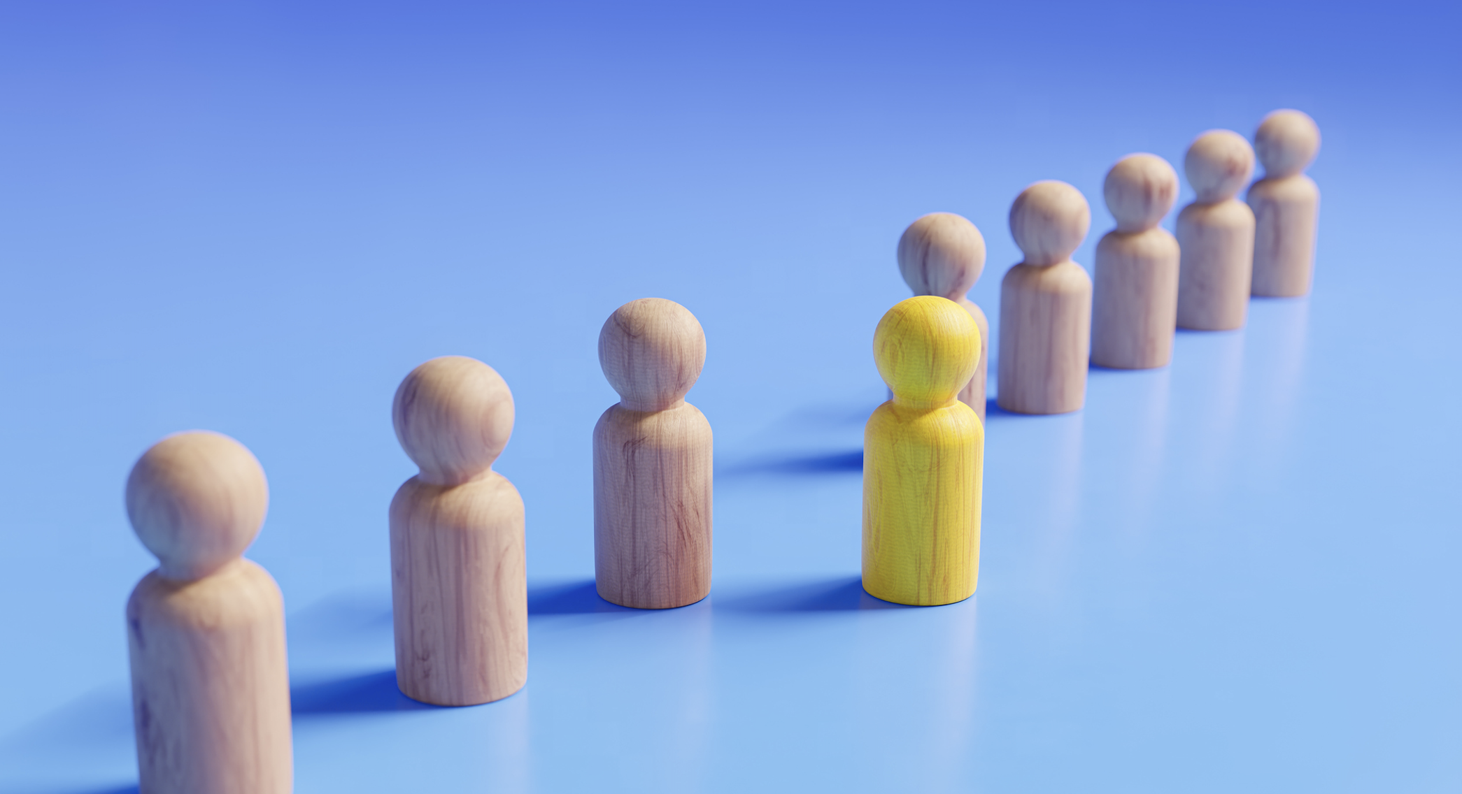 Wooden figures stand in a diagonal line against a blue field, with one yellow figure one step forward.