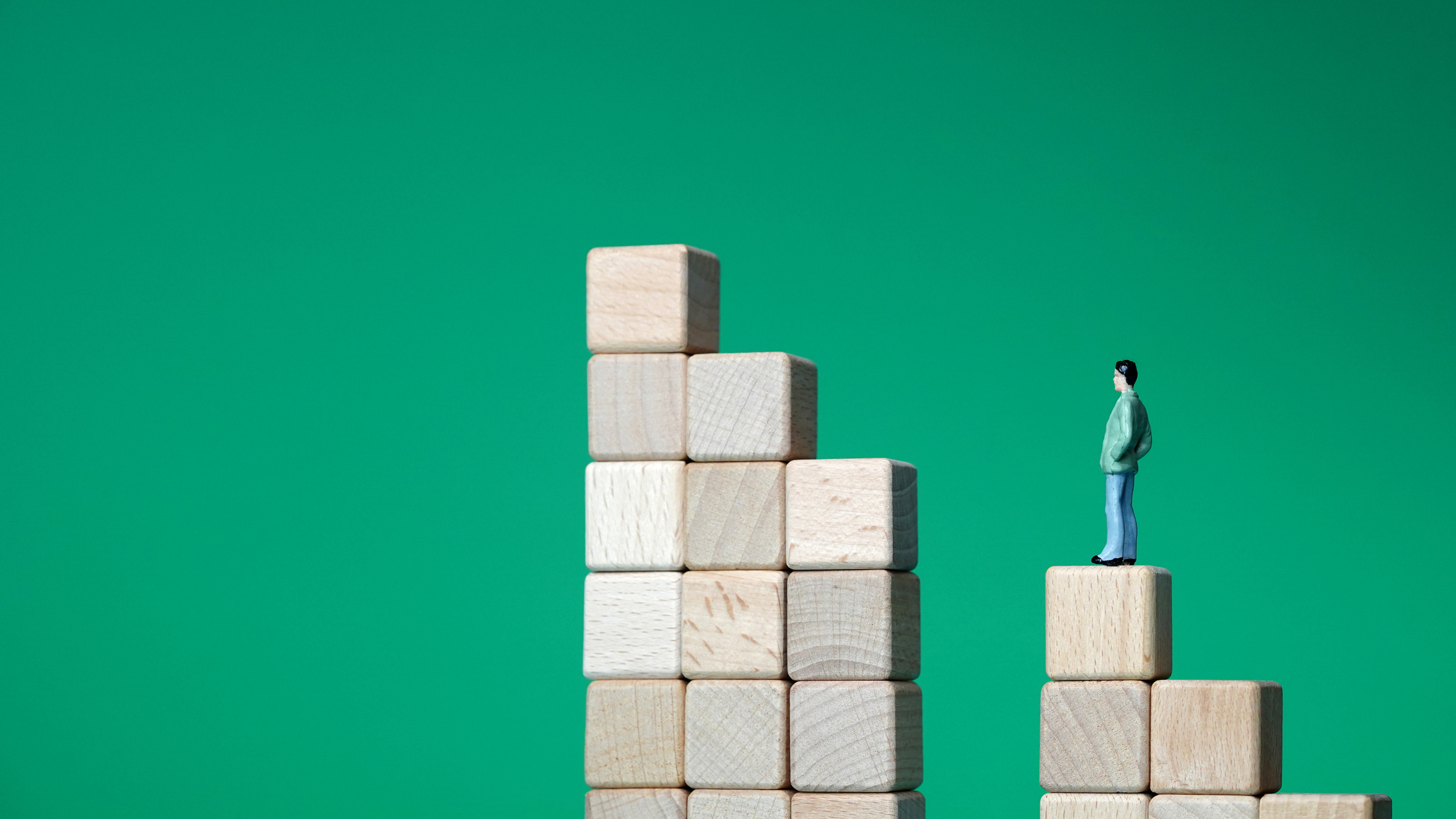 A photo of a small toy figure of a man standing on a staircase of blocks split by a large gap
