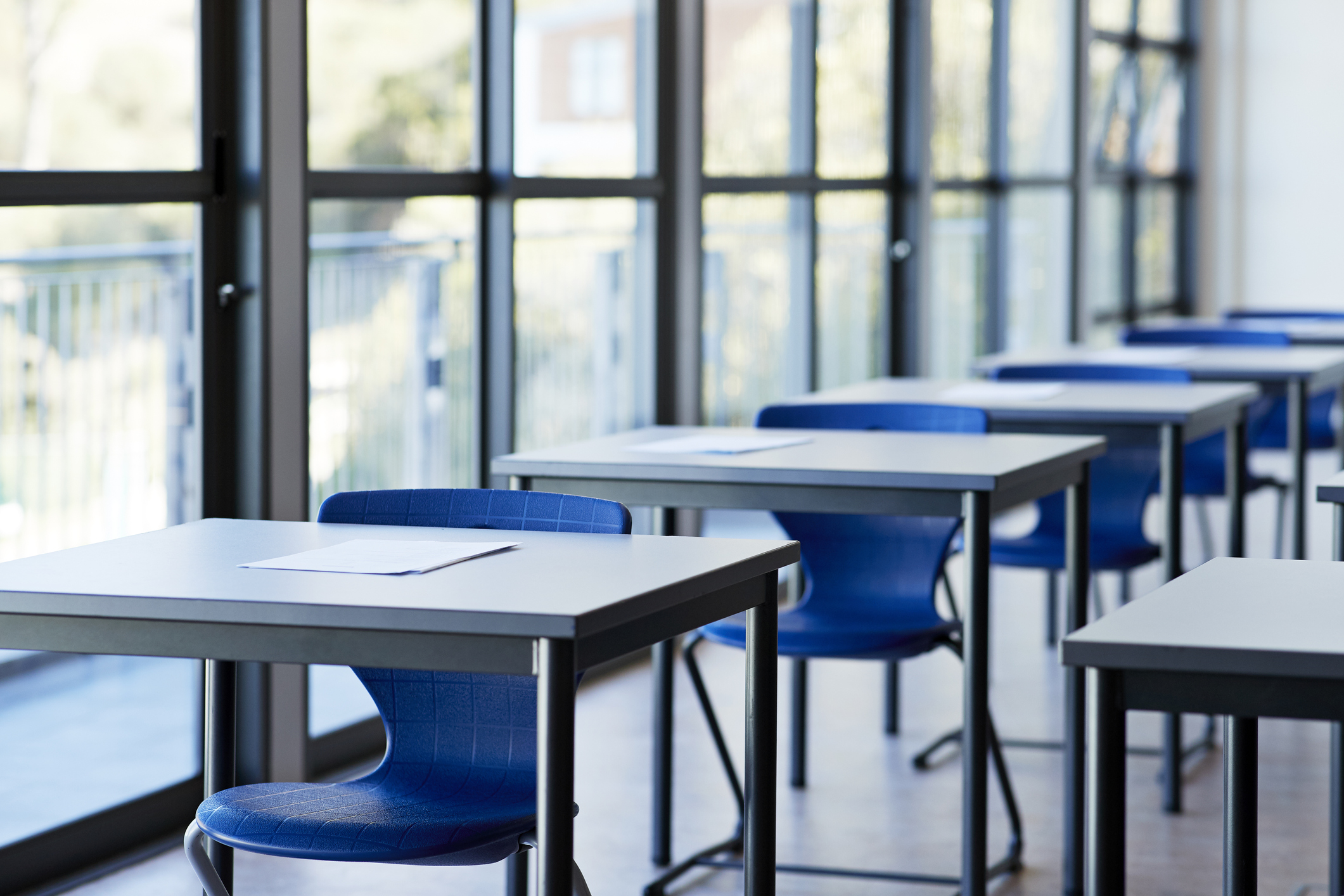 A photo of blue classroom desks seen at a diagonal.