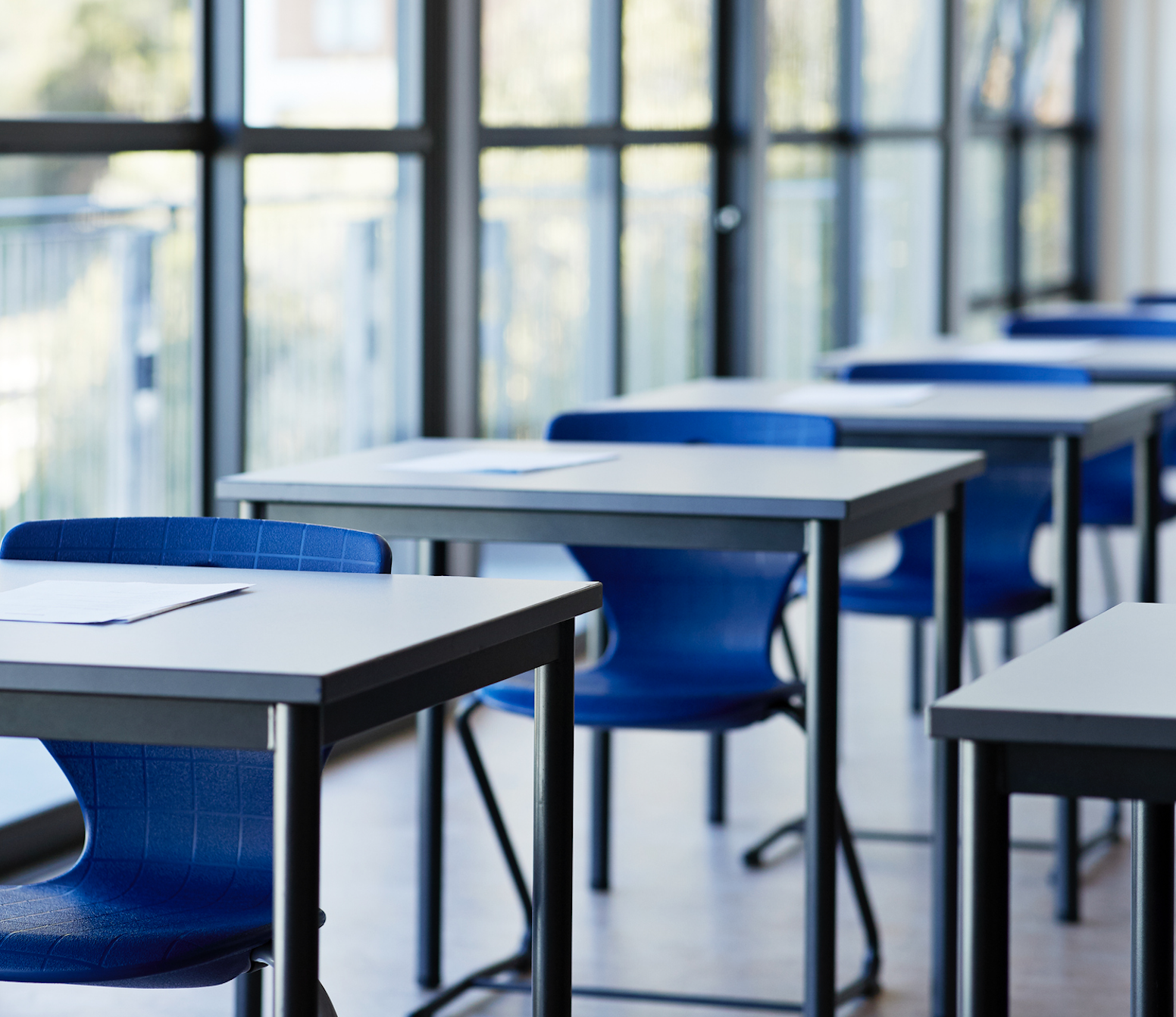 A photo of blue classroom desks seen at a diagonal.