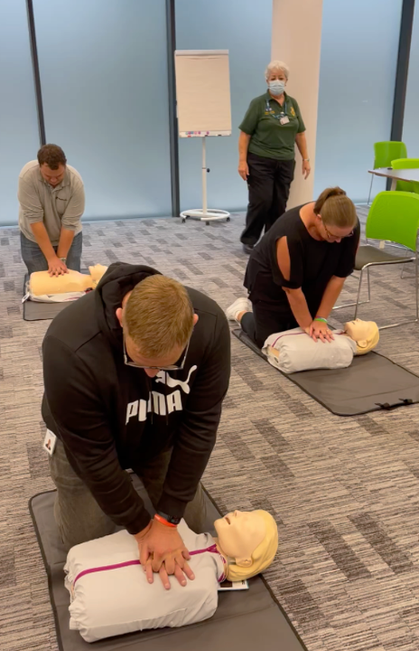 Group of four Tanium UK team members practicing CPR on CPR manikins