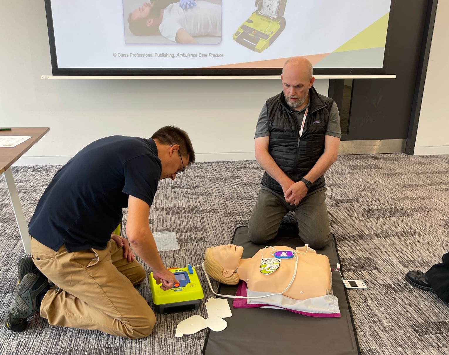 Two members of Tanium’s UK team practicing CPR on a CPR manikin