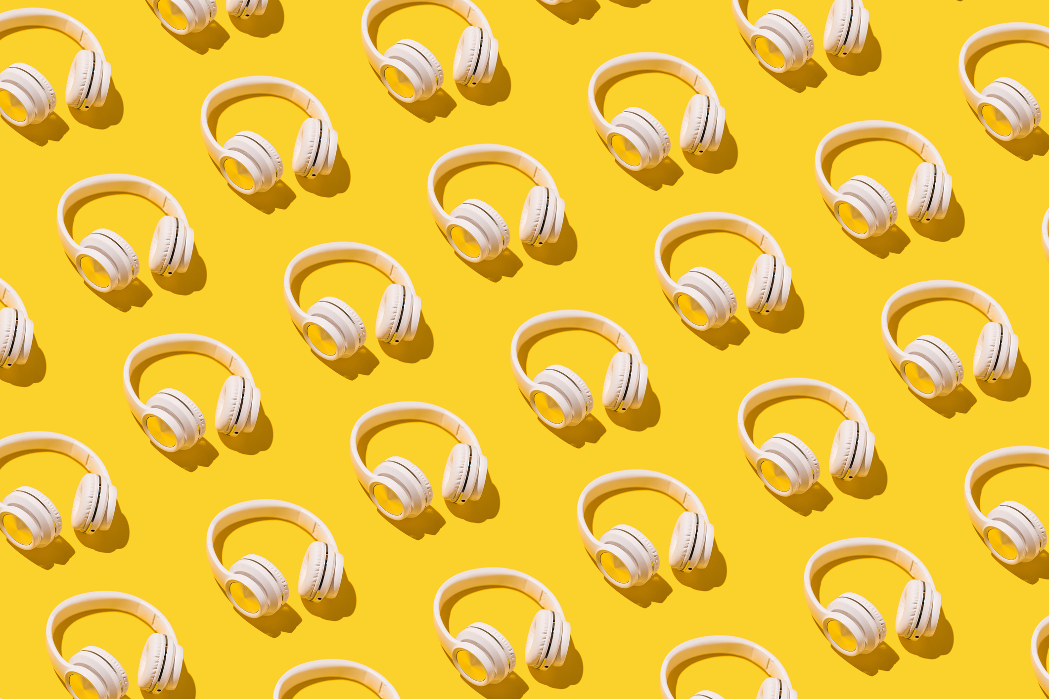 An image of headphones in diagonal rows against a bright yellow field.